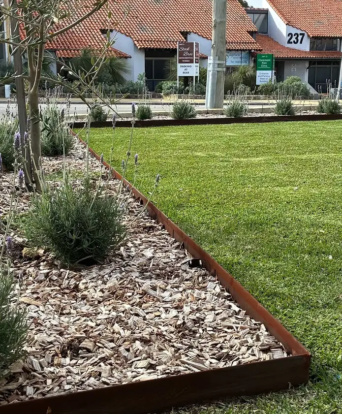 Fresh lawn beside a mulched garden bed with steel edging