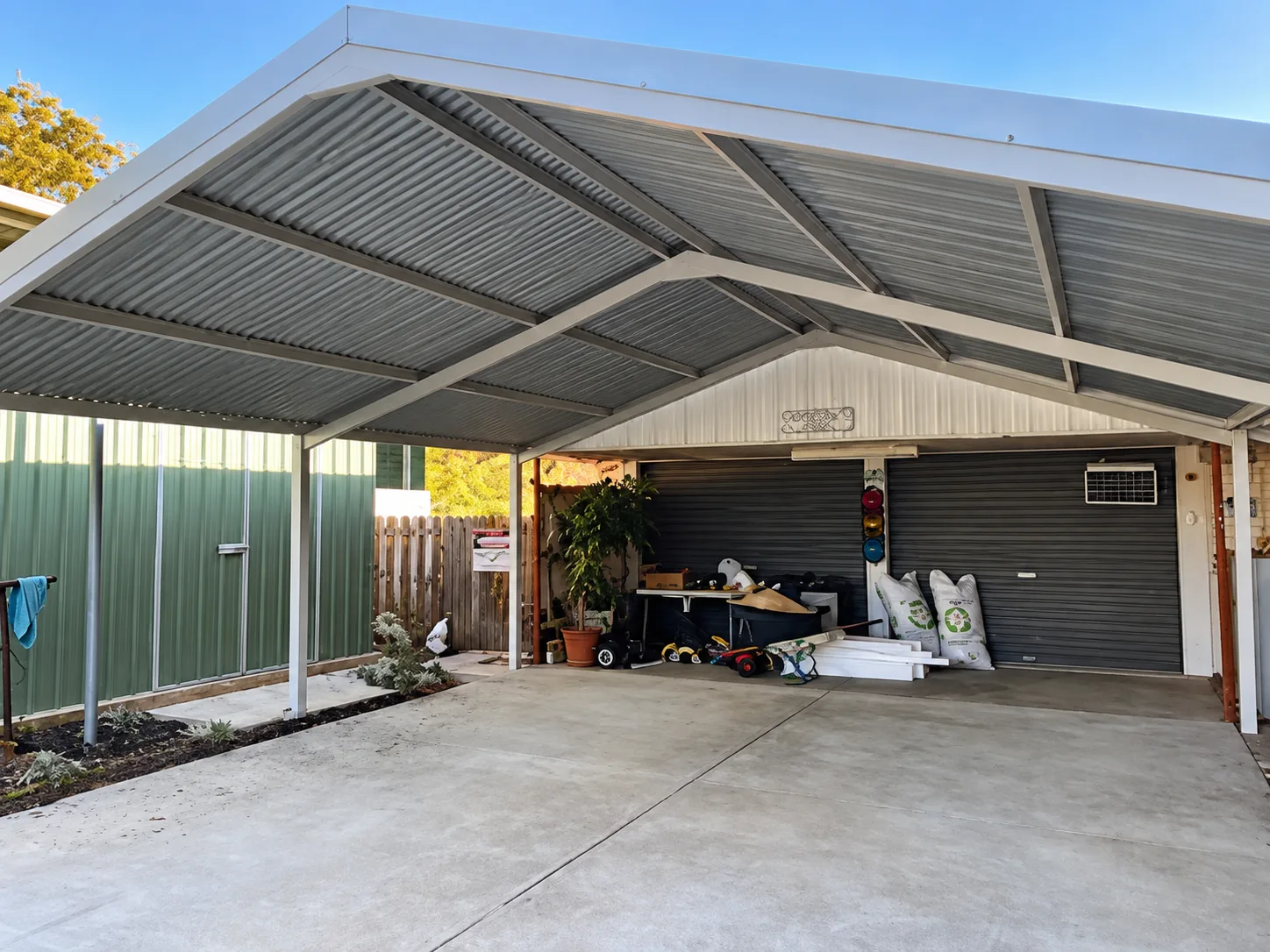 Residential double carport installation with a gabled metal roof beside a garage.
