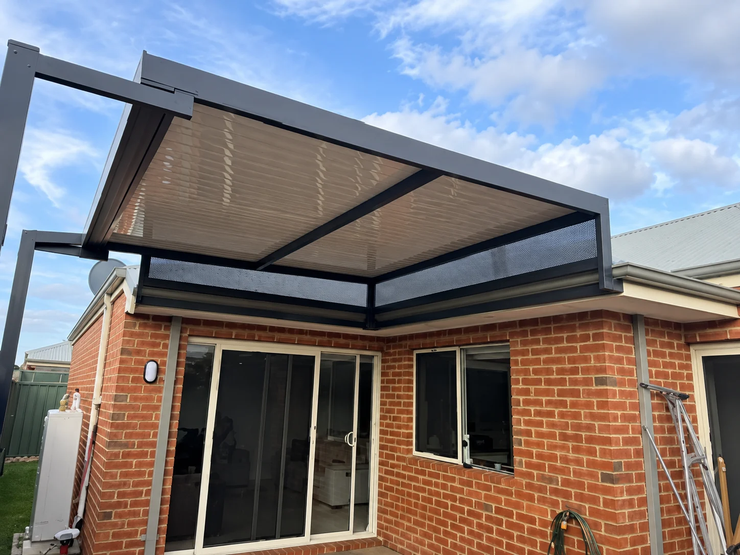 Modern patio roof extension attached to a brick home with sliding doors.