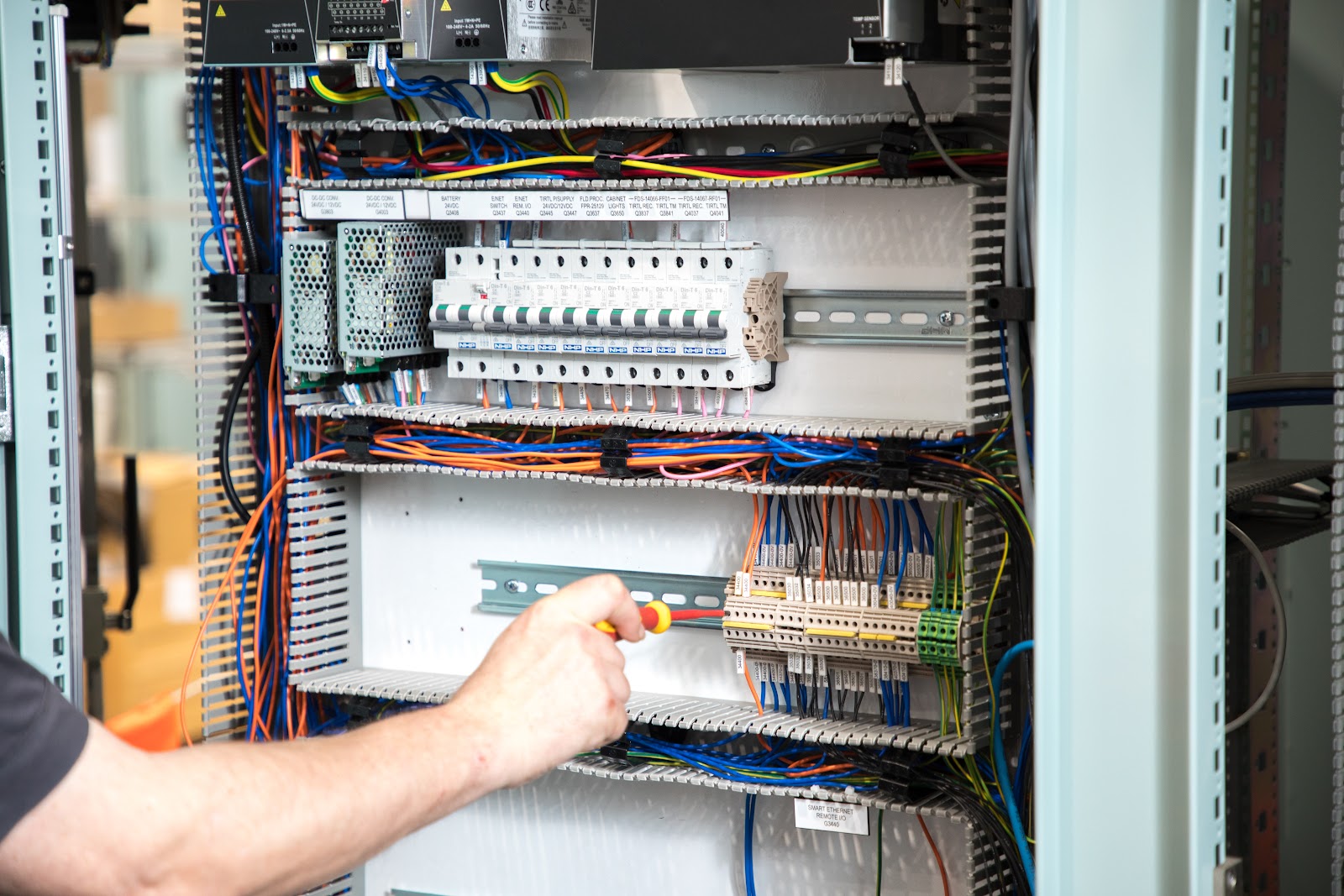 Close-up of technician hands working on electrical control panel with wiring
