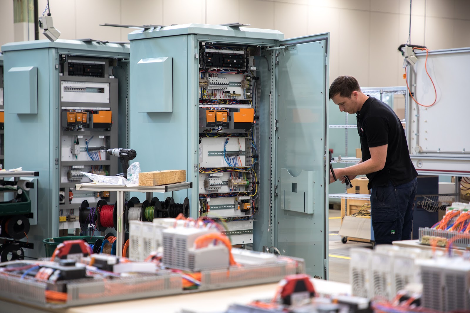 Technician working on industrial control system cabinet with electronic components