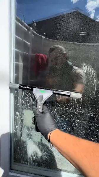 Commercial window cleaner using water fed pole system on building exterior