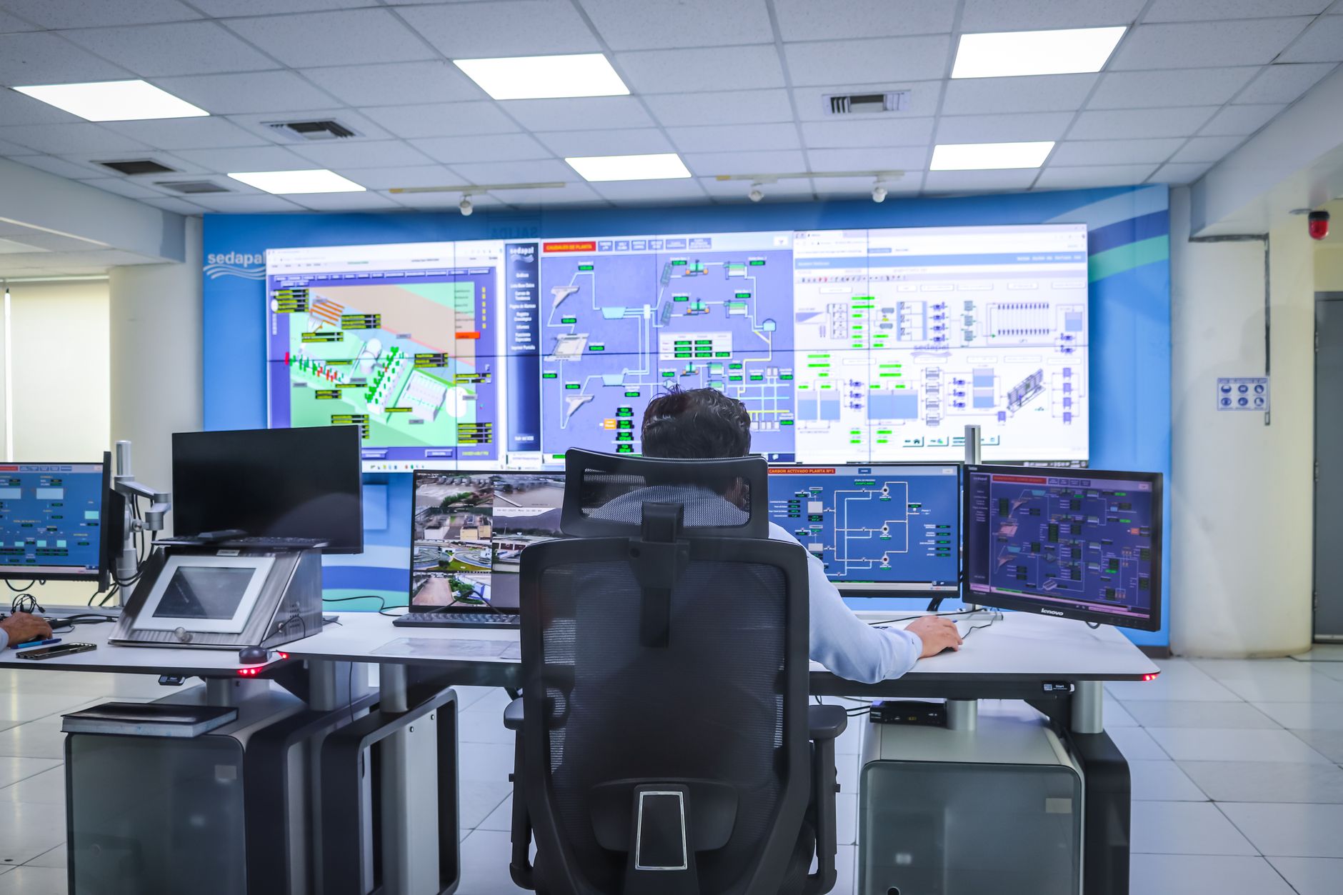 Operator monitoring computer screens displaying automation control system schematics